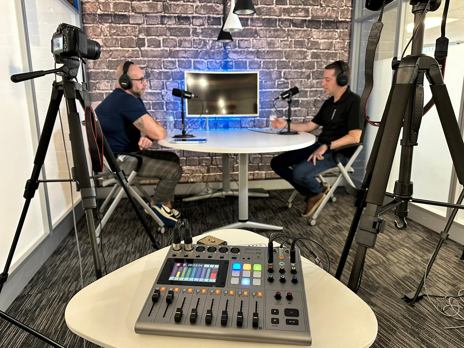 A photo of a podcast studio with cameras and soundboard.